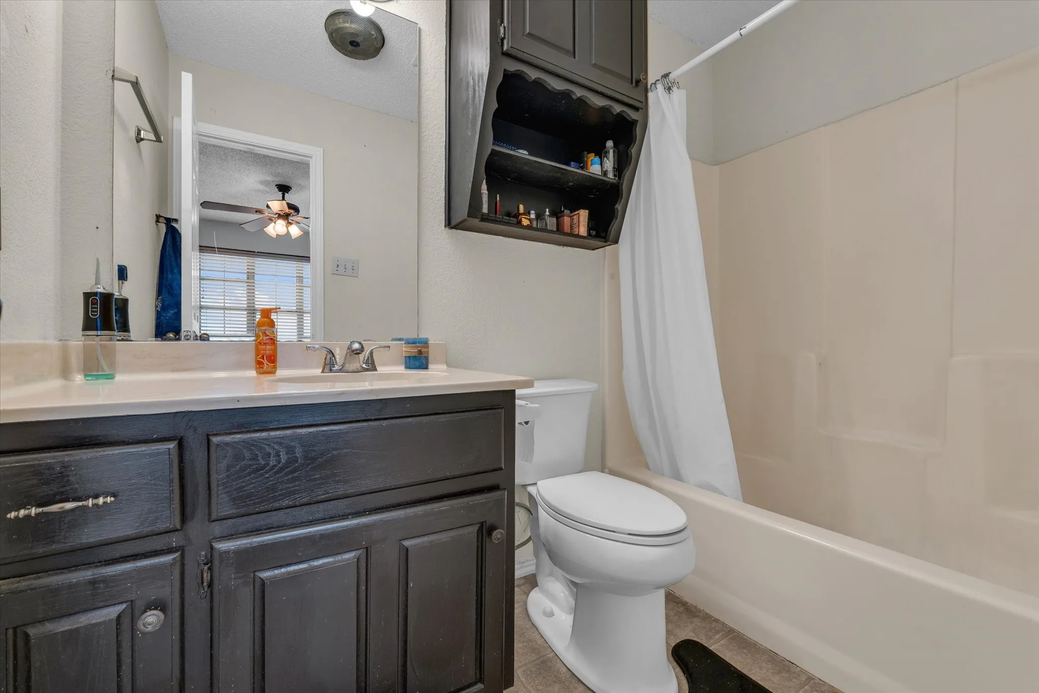 Full bath featuring shower / bath combo, vanity, light tile patterned floors, a textured ceiling, and ceiling fan