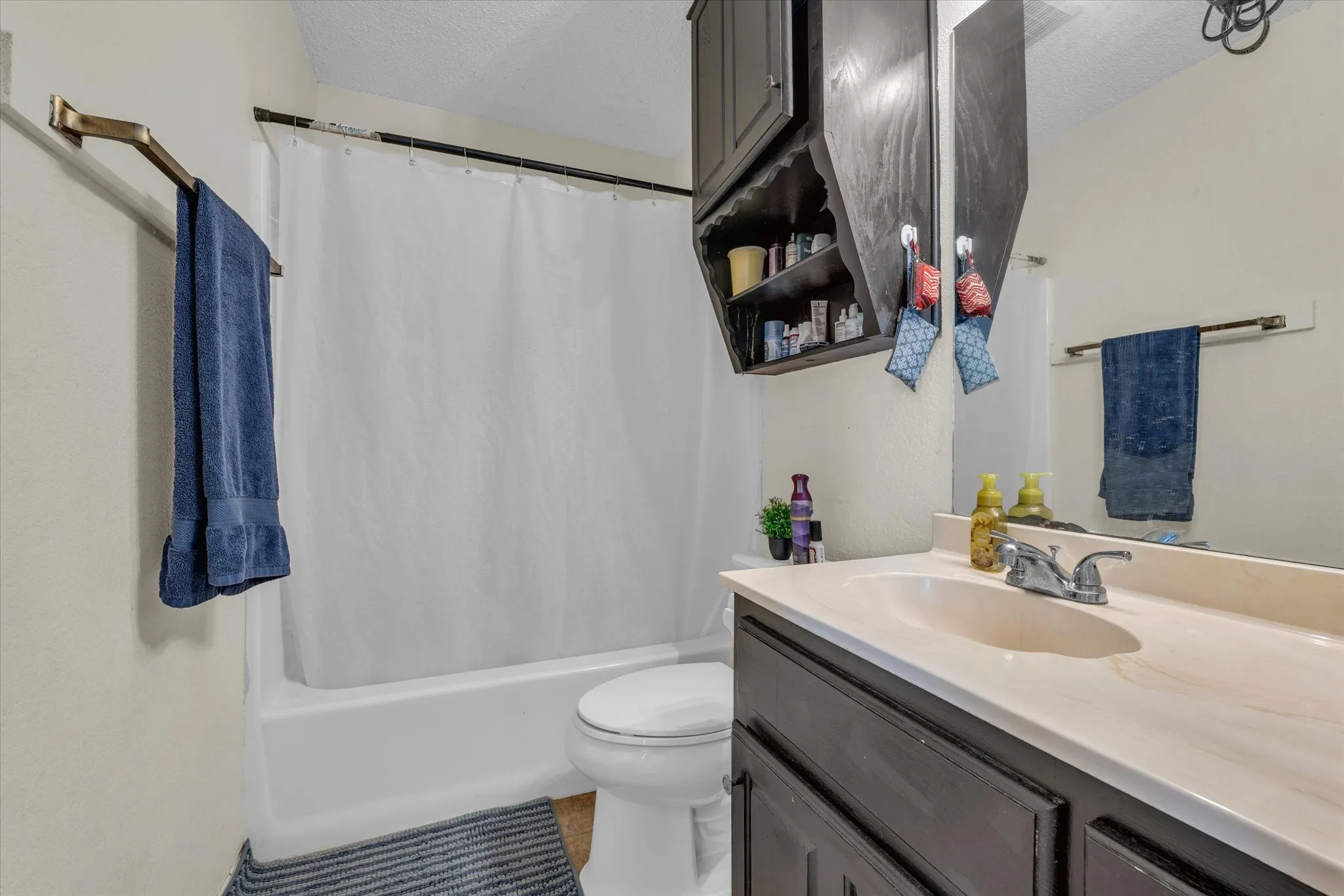 Full bathroom featuring vanity, shower / bath combination with curtain, a textured ceiling, and light tile patterned flooring