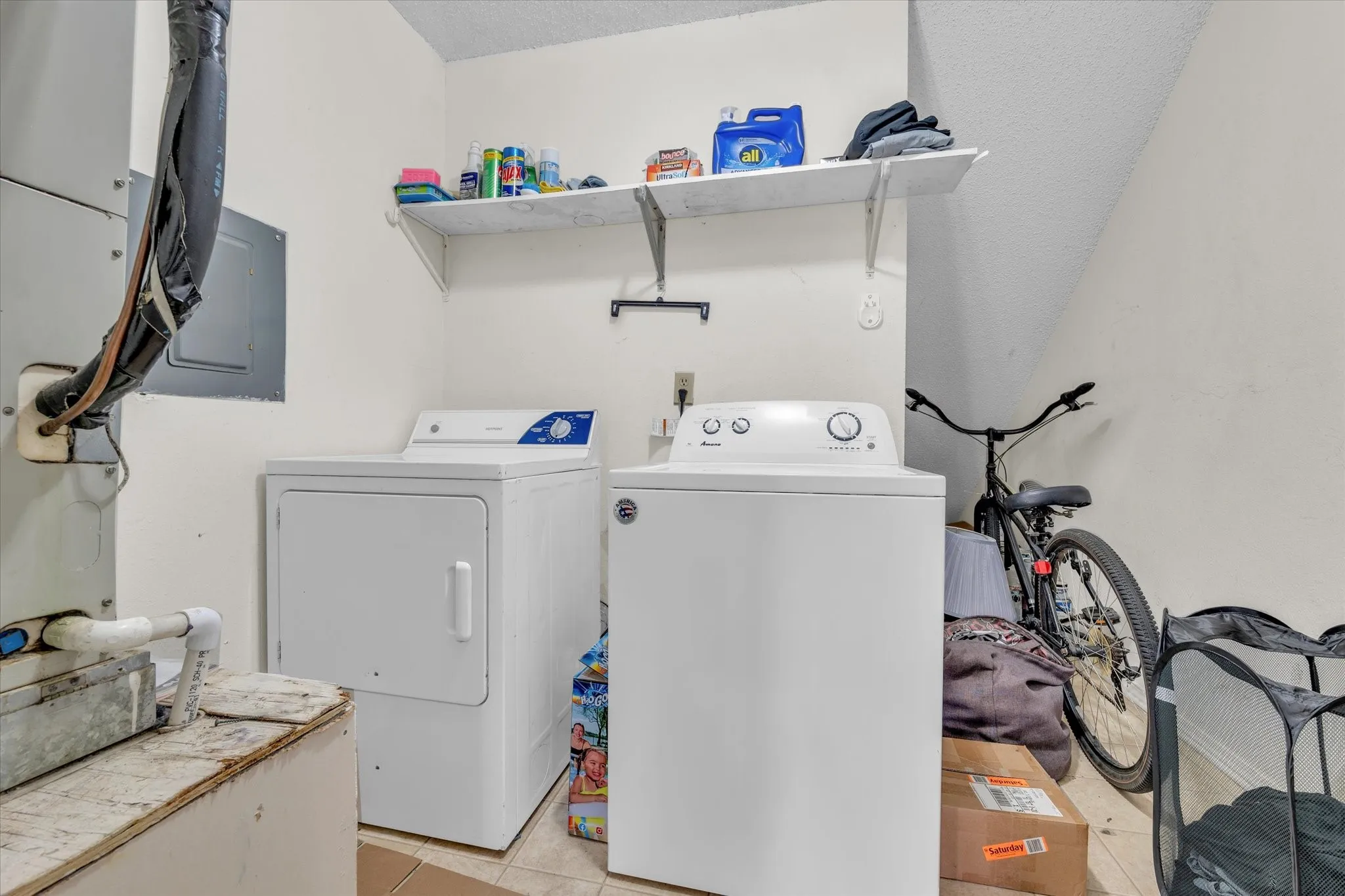 Laundry room featuring light tile patterned flooring, electric panel, separate washer and dryer, heating unit, and a textured ceiling