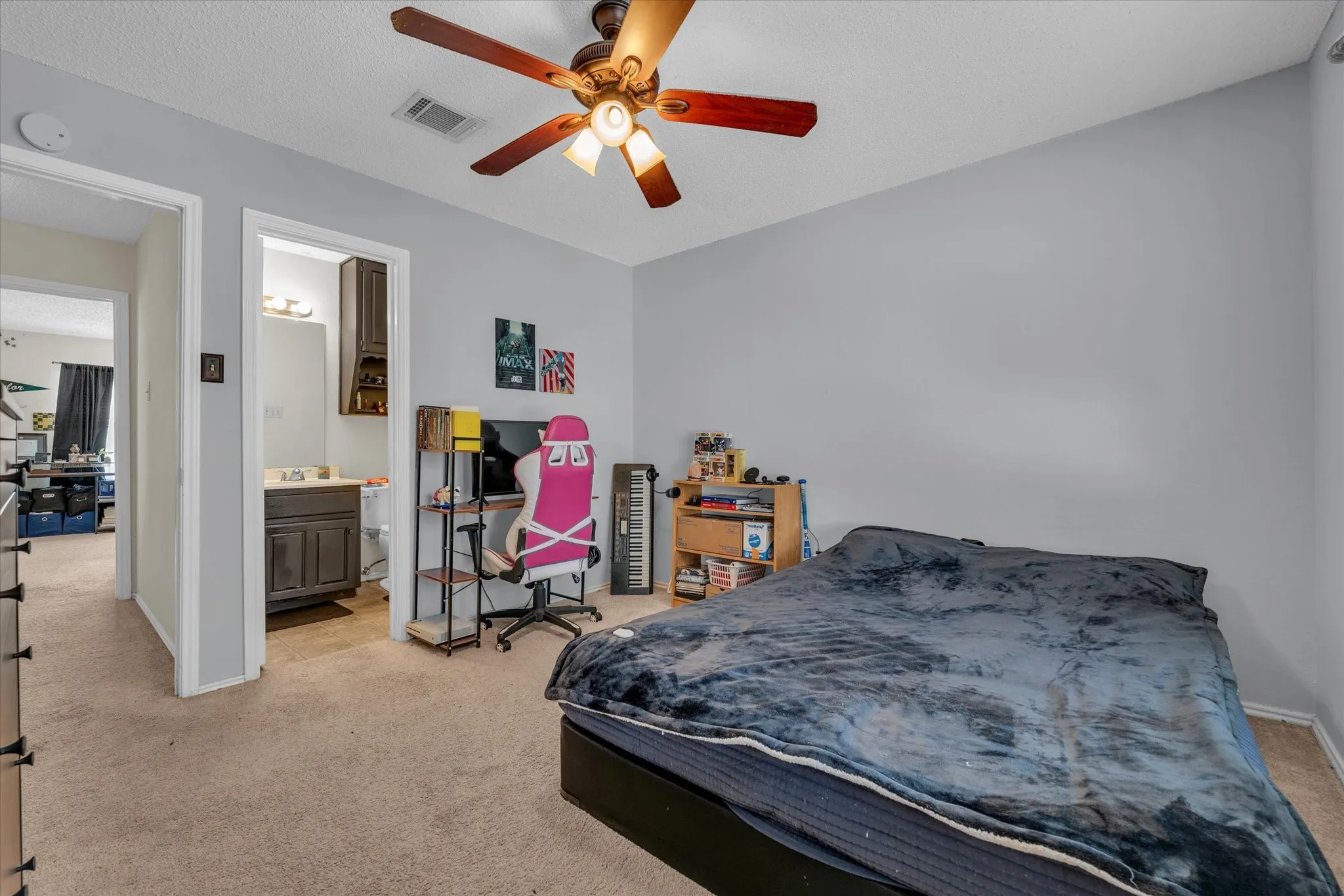 Bedroom with light carpet, ensuite bathroom, and a ceiling fan