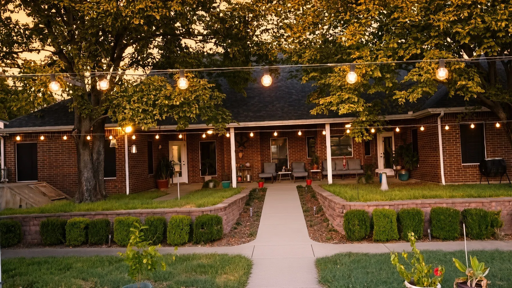 Brick exterior with a covered front porch, concrete pathway, and landscaped retaining wall