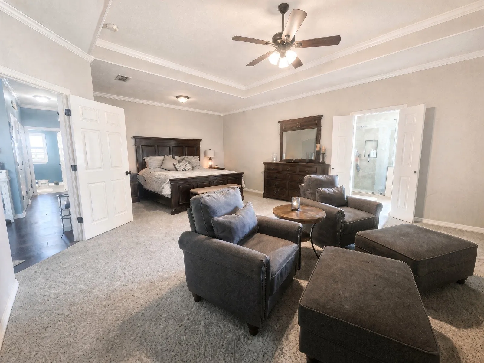 Carpeted flooring, tray ceiling with crown molding, and a ceiling fan with light fixture