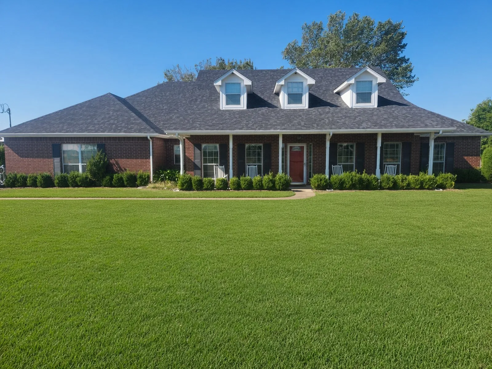 Brick exterior with a covered front porch featuring white columns and a red entry door