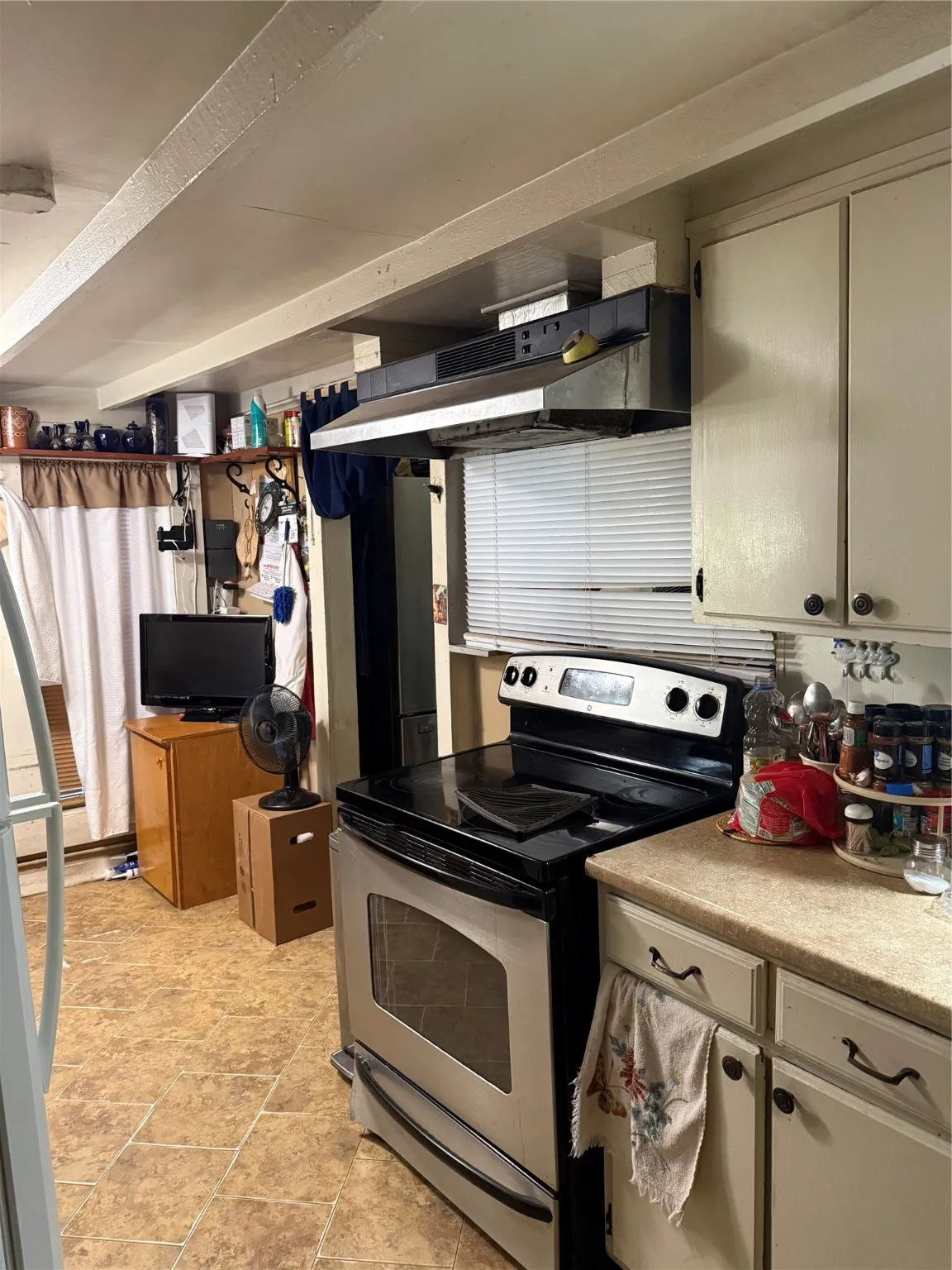 Kitchen featuring range, ventilation hood, light countertops, and refrigerator