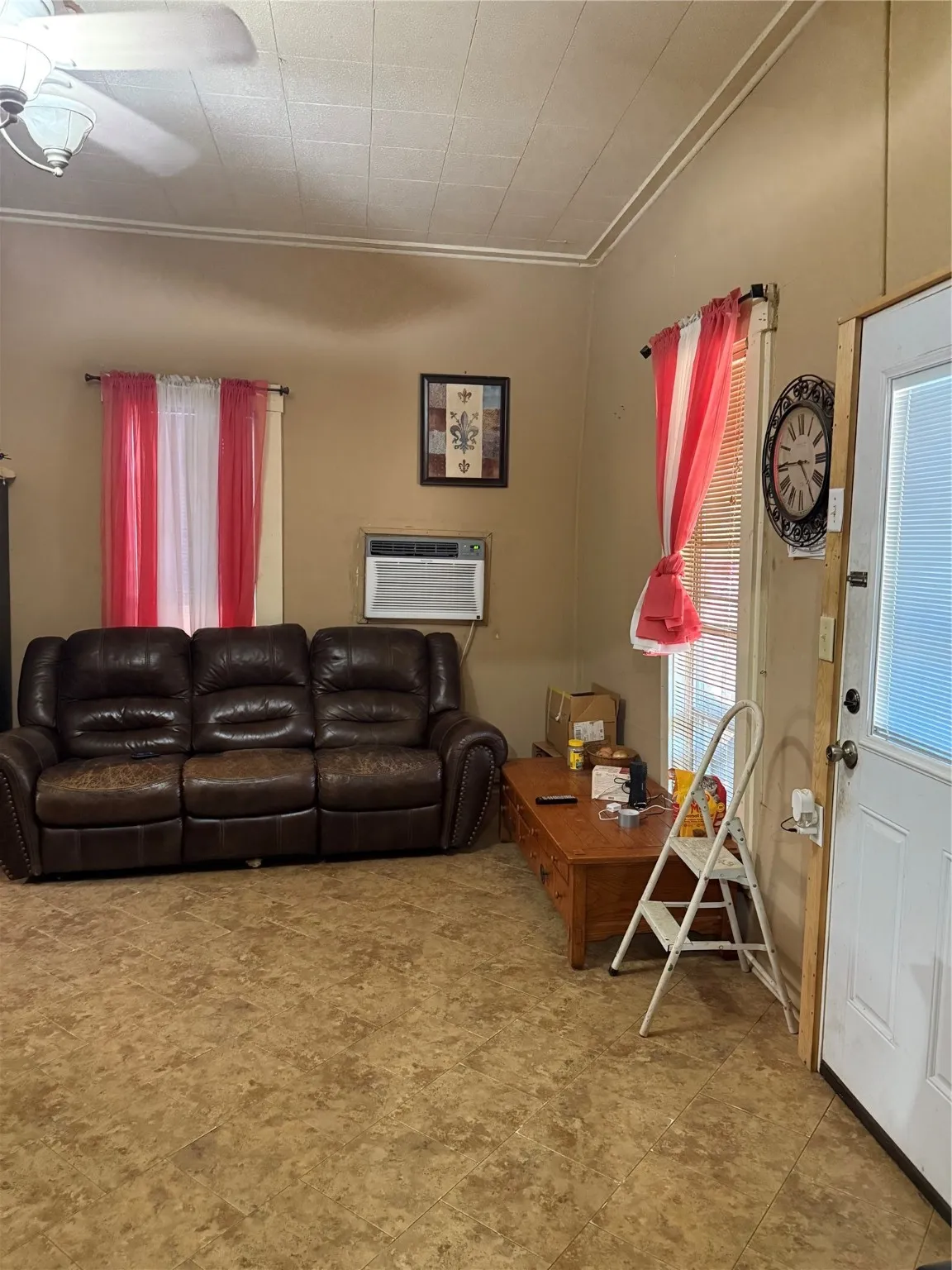 Living room with ornamental molding and a wall mounted AC