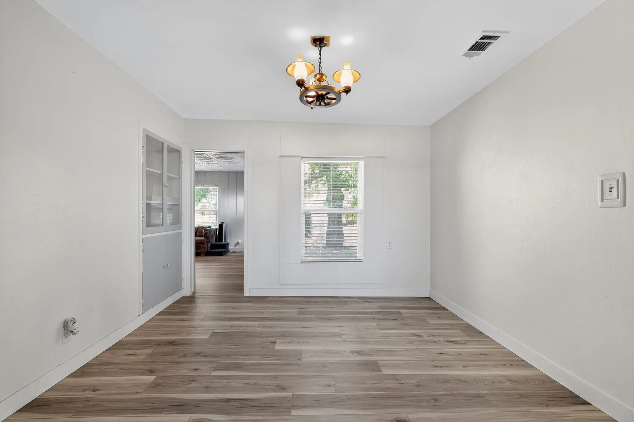 Unfurnished room with wood finished floors and a chandelier