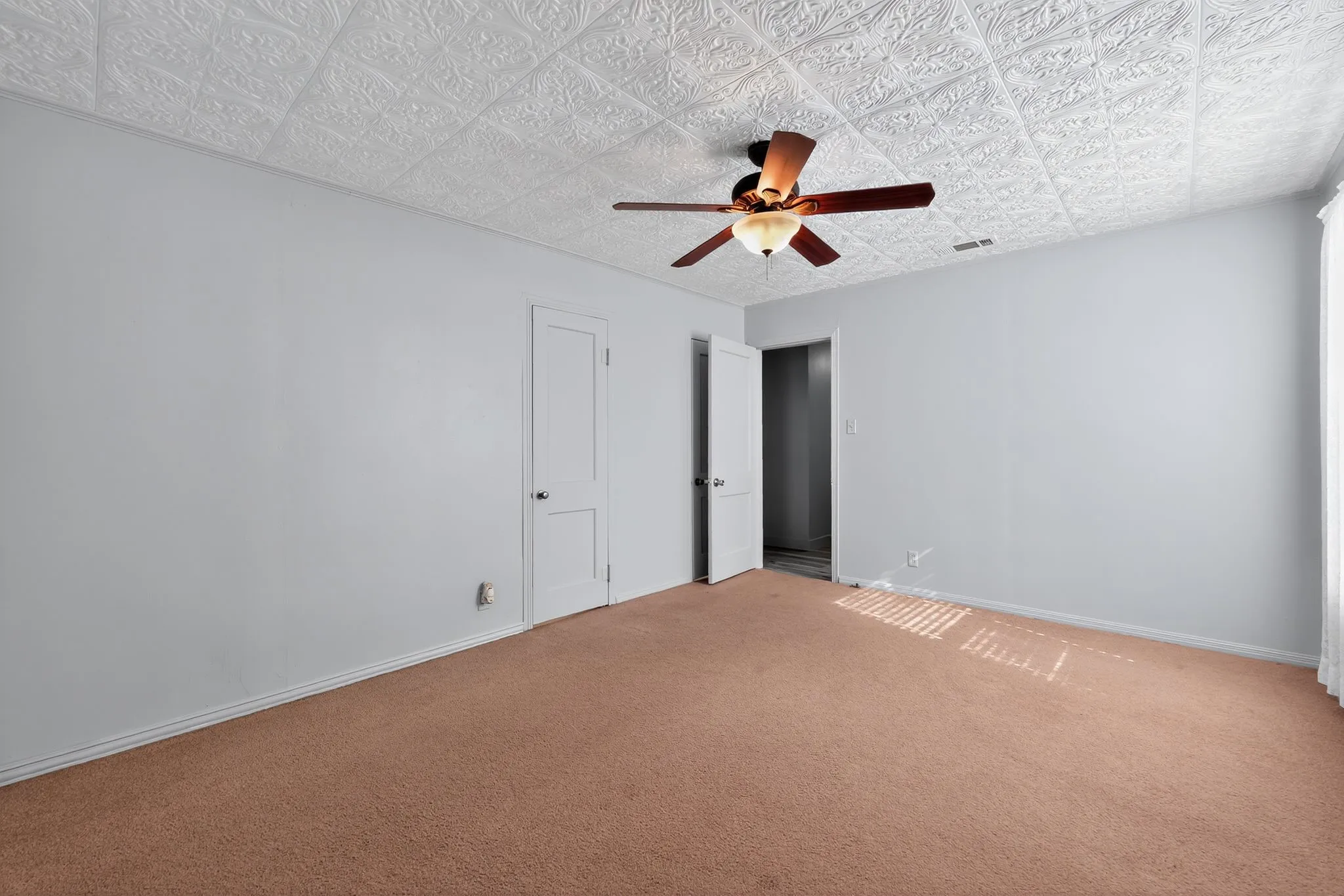 Unfurnished bedroom with carpet floors, ceiling fan, and an ornate ceiling