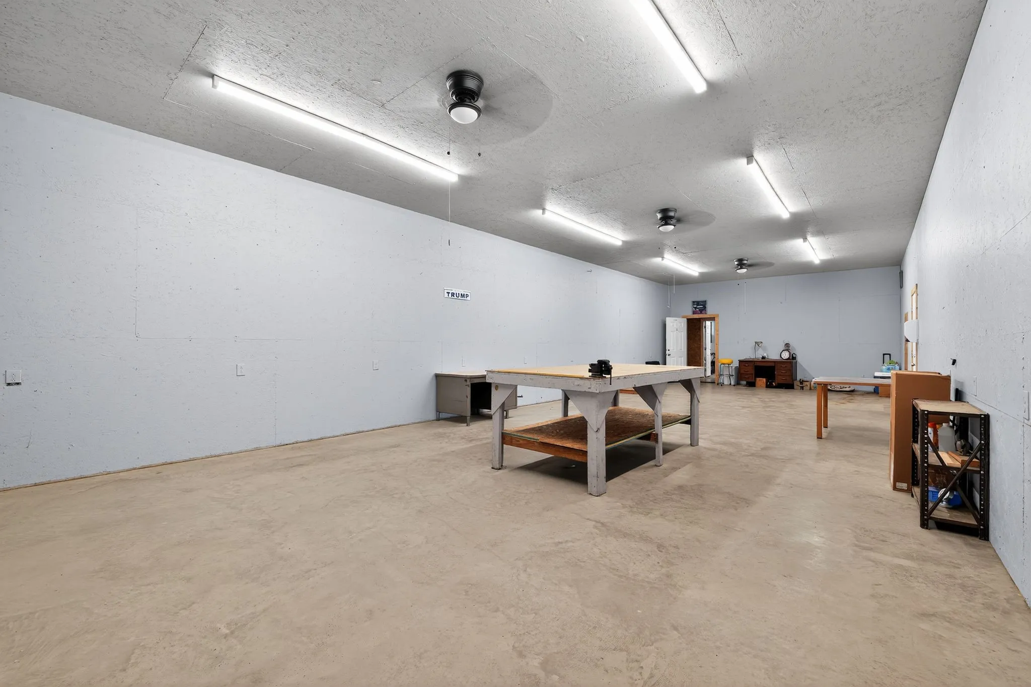 Rec room with ceiling fan, concrete flooring, a textured ceiling, and a workshop area