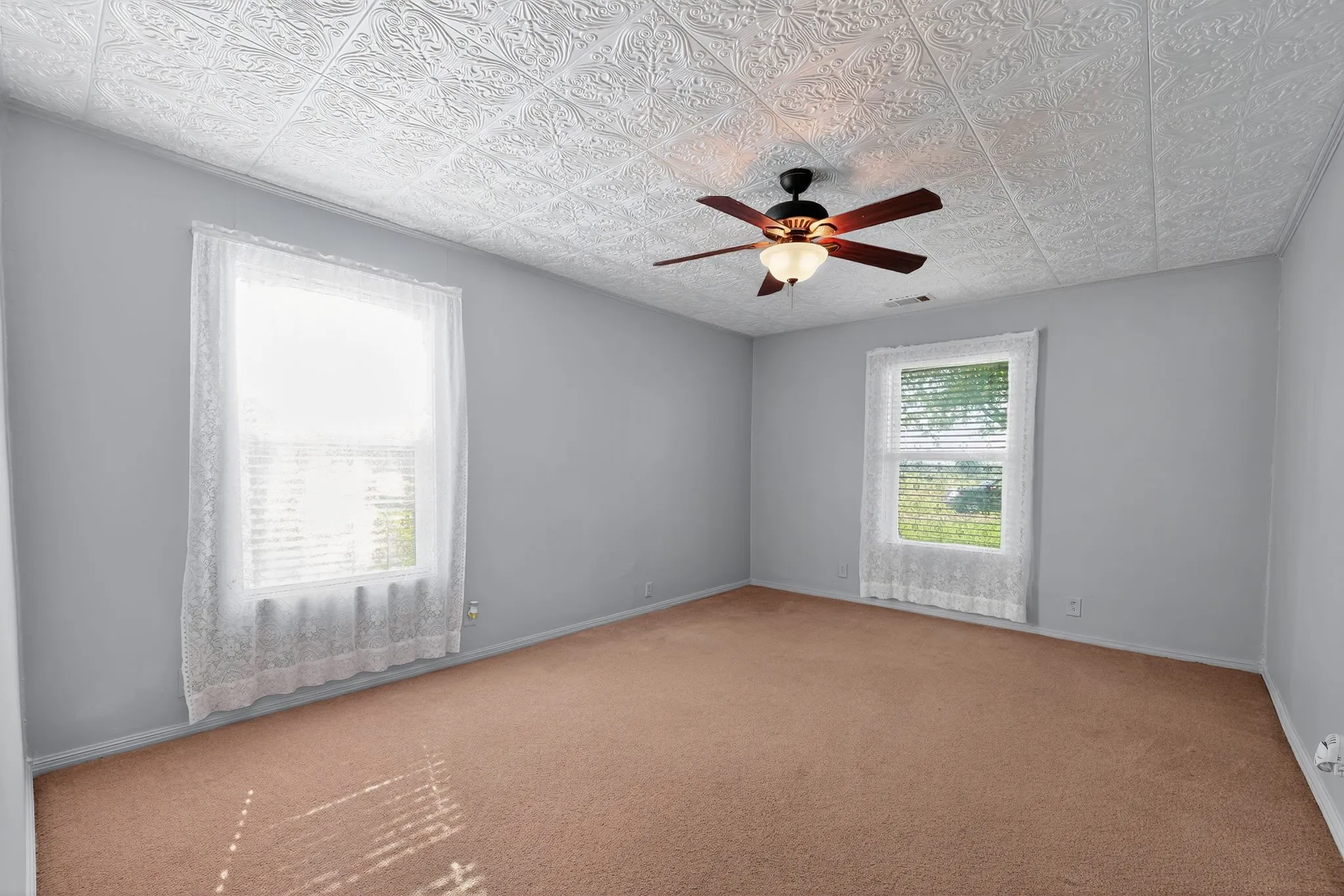 Spare room with carpet flooring, a ceiling fan, and an ornate ceiling