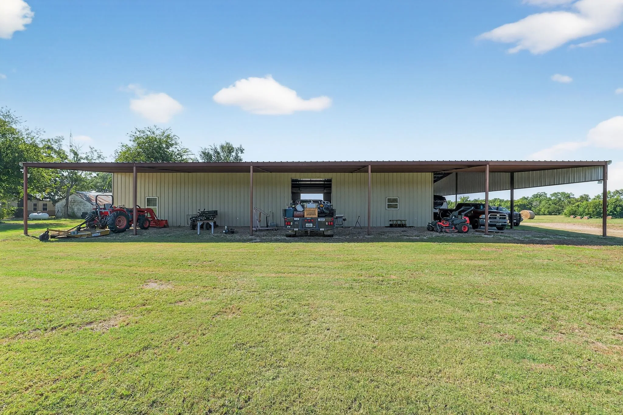 View of pole building with a carport and a yard