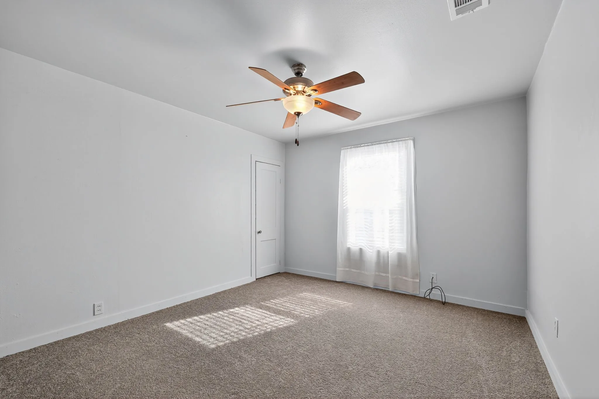 Carpeted empty room with baseboards and a ceiling fan