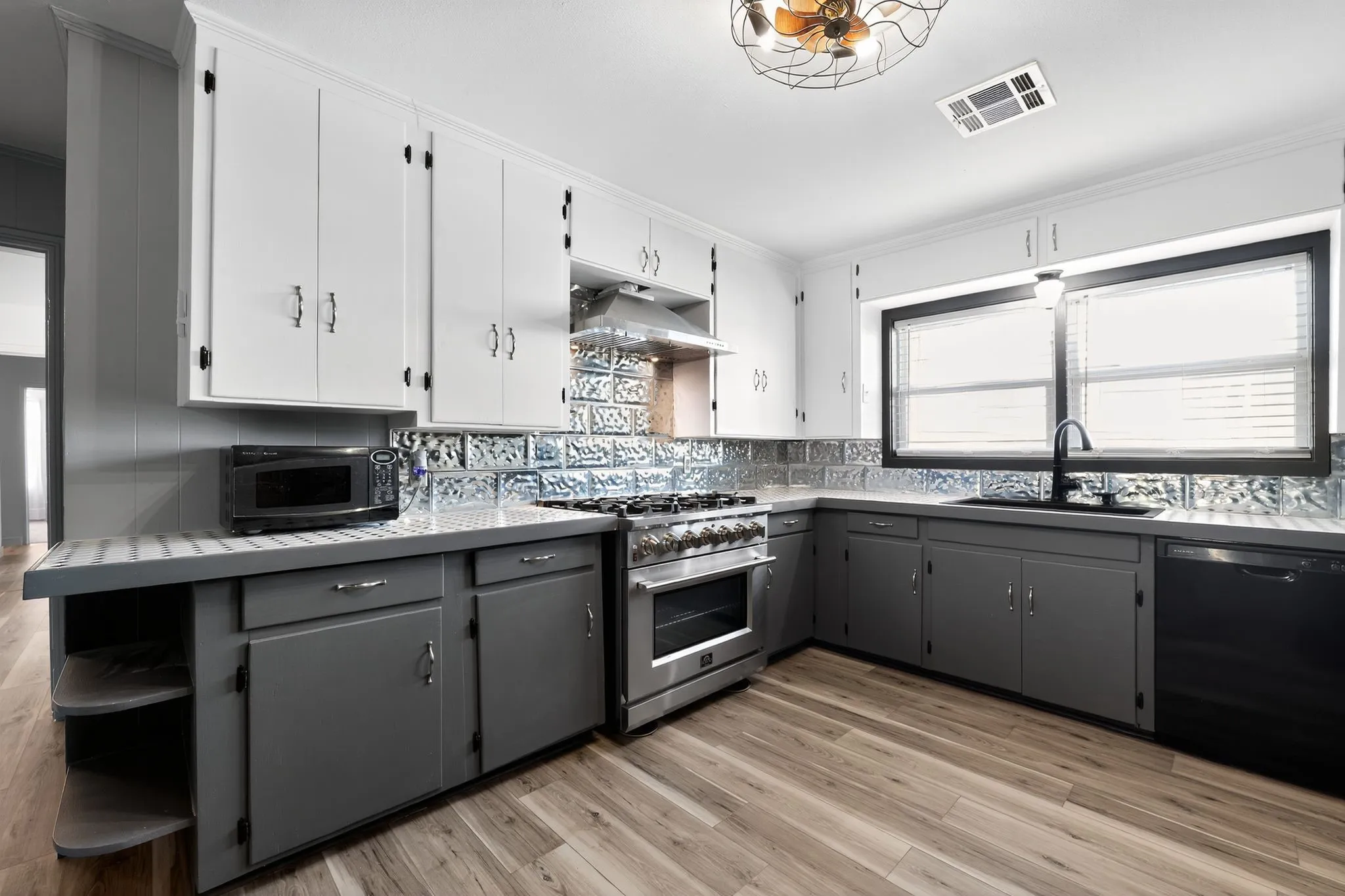 Kitchen with gray cabinetry, white cabinetry, light wood-type flooring, and black appliances