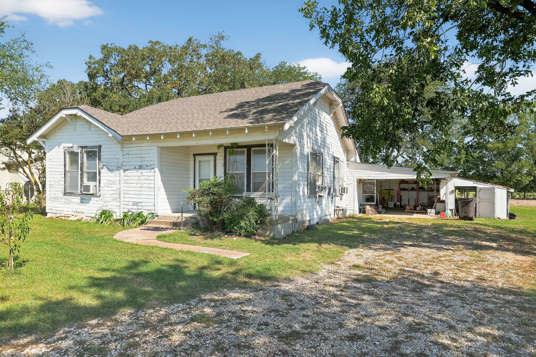 View of property exterior featuring a shingled roof, a lawn, a patio, and an outbuilding
