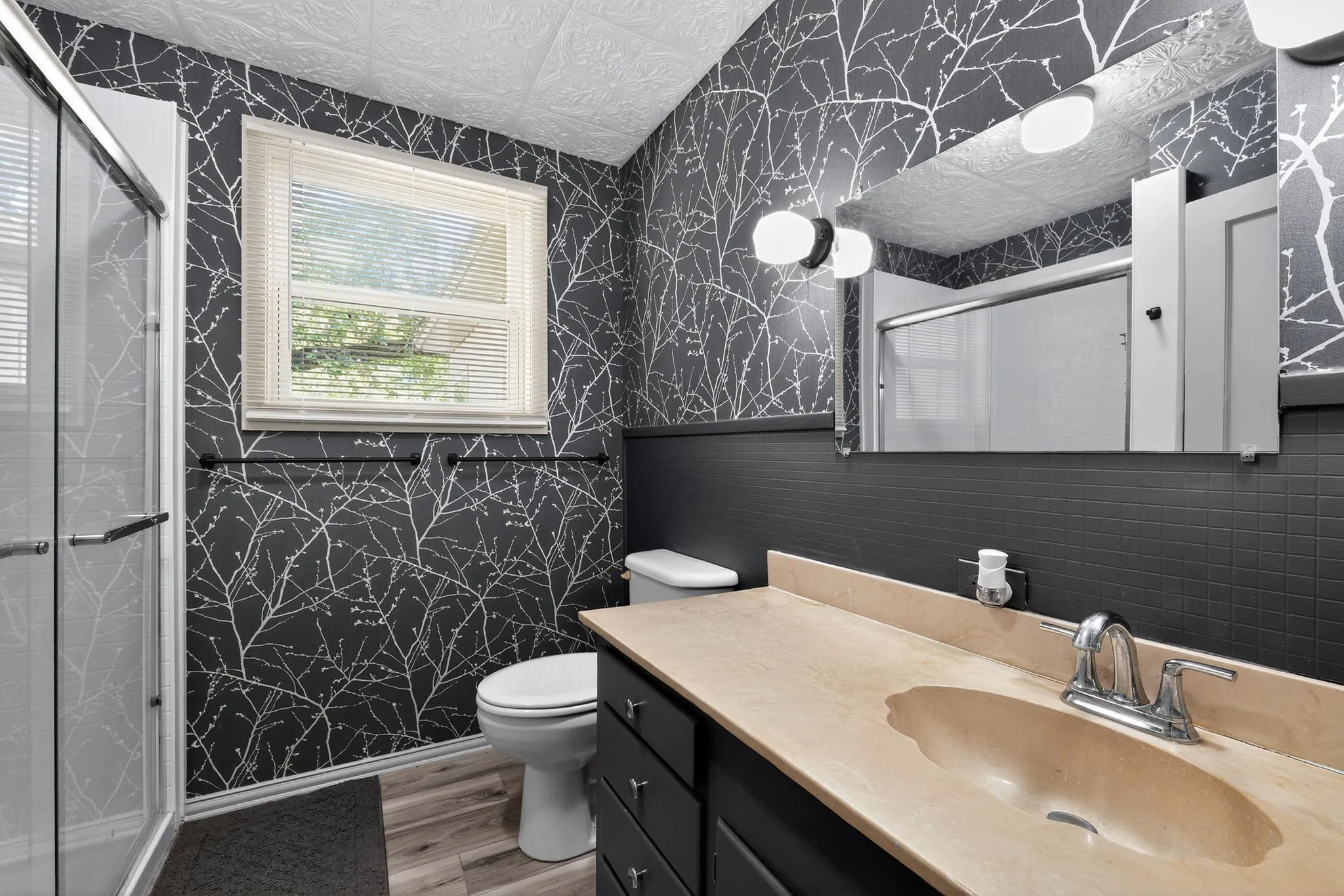 Bathroom featuring wallpapered walls, light wood-type flooring, an ornate ceiling, vanity, and a stall shower