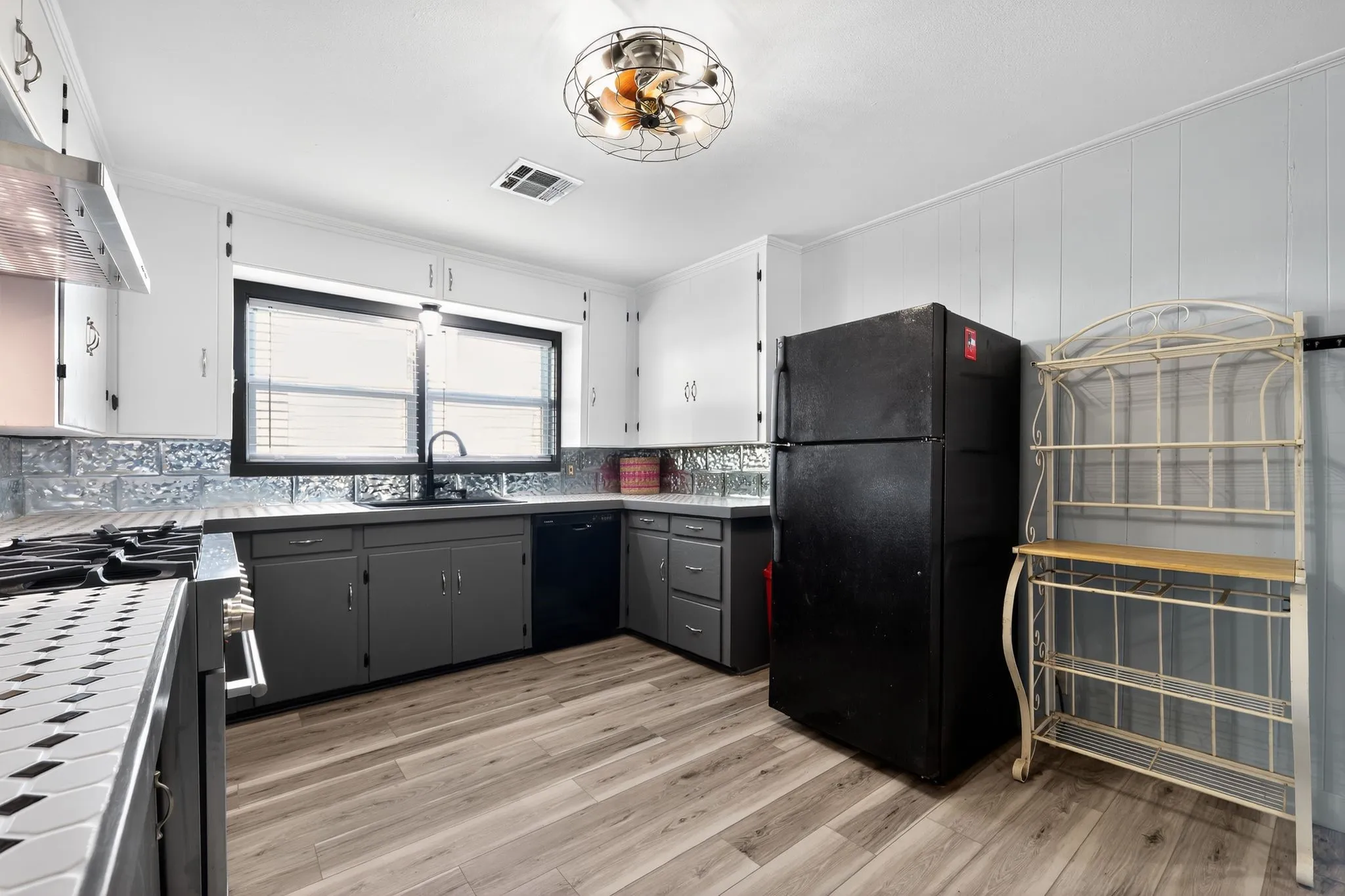 Kitchen with gray cabinetry, black appliances, white cabinetry, light wood-style floors, and extractor fan