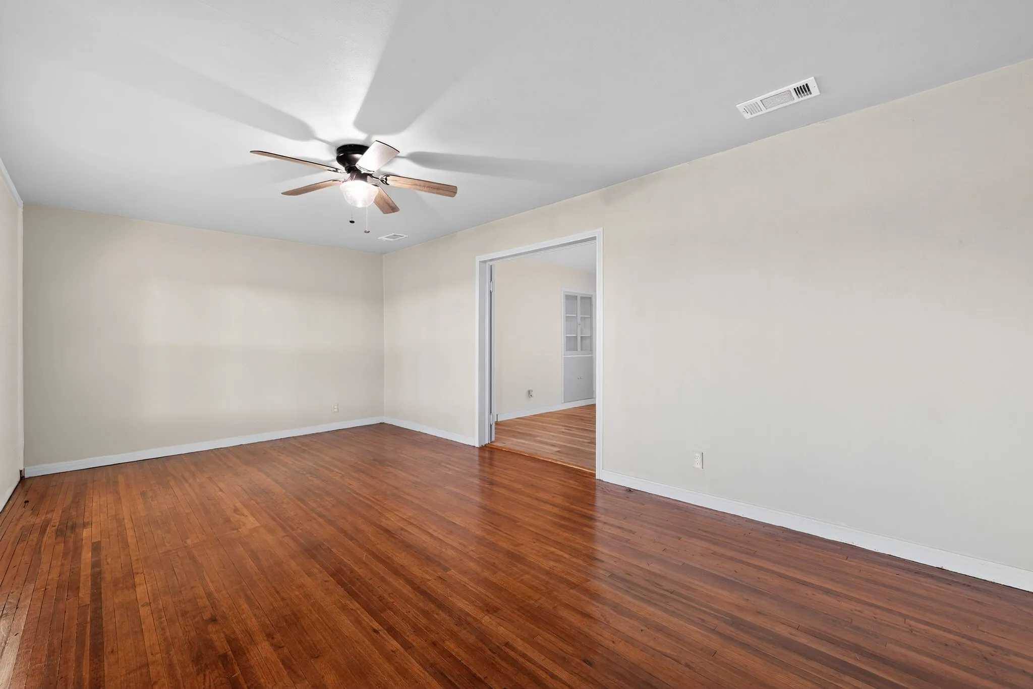 Empty room with dark wood-style floors and a ceiling fan
