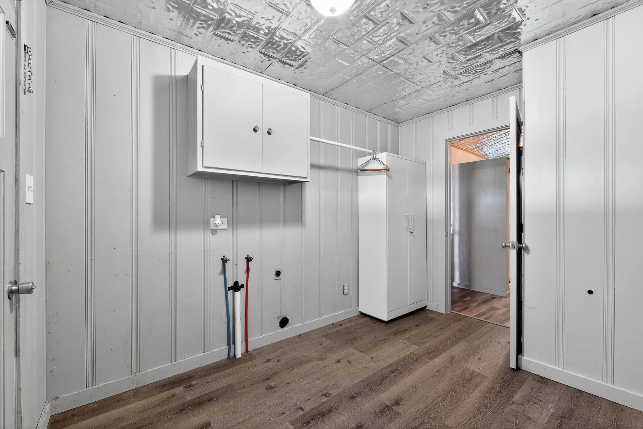 Laundry area featuring dark wood-style floors, cabinet space, washer hookup, an ornate ceiling, and wood walls
