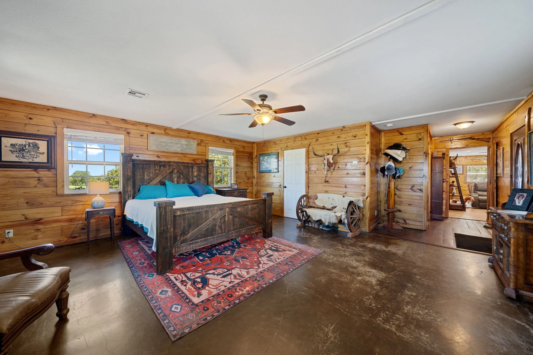Bedroom with wood walls, finished concrete floors, and a ceiling fan