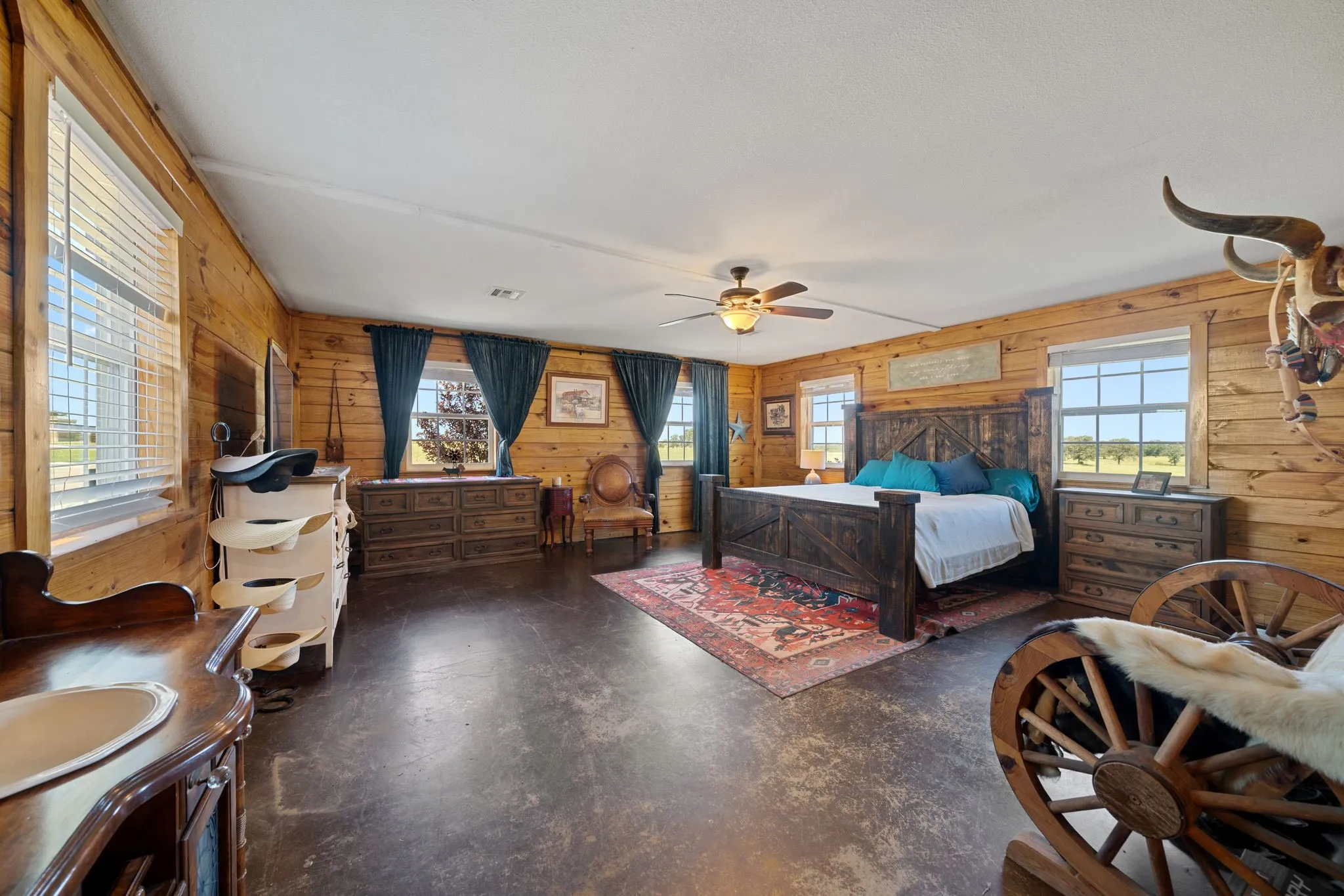 Bedroom with wood walls, finished concrete floors, and a ceiling fan
