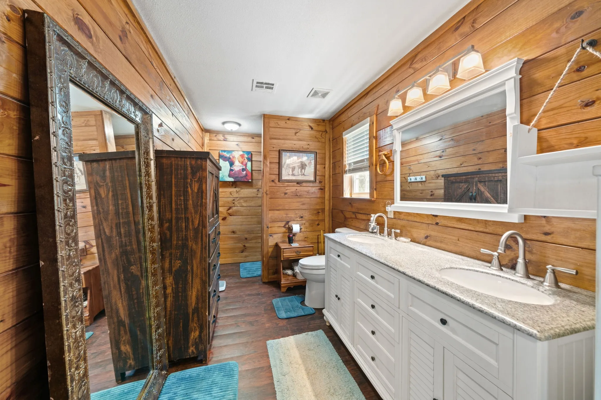 Full bathroom featuring wooden walls, double vanity, and dark wood-type flooring