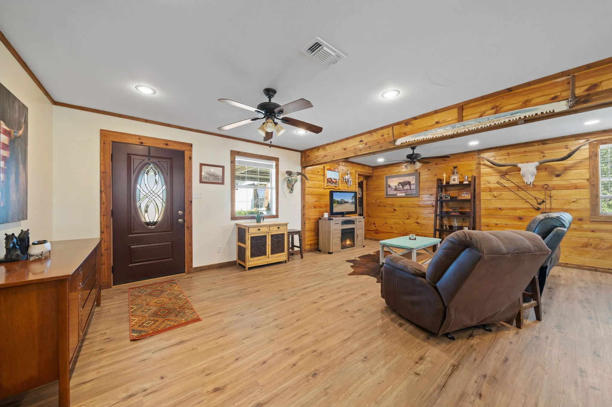 Living room featuring recessed lighting, light wood-style floors, ceiling fan, wood walls, and ornamental molding