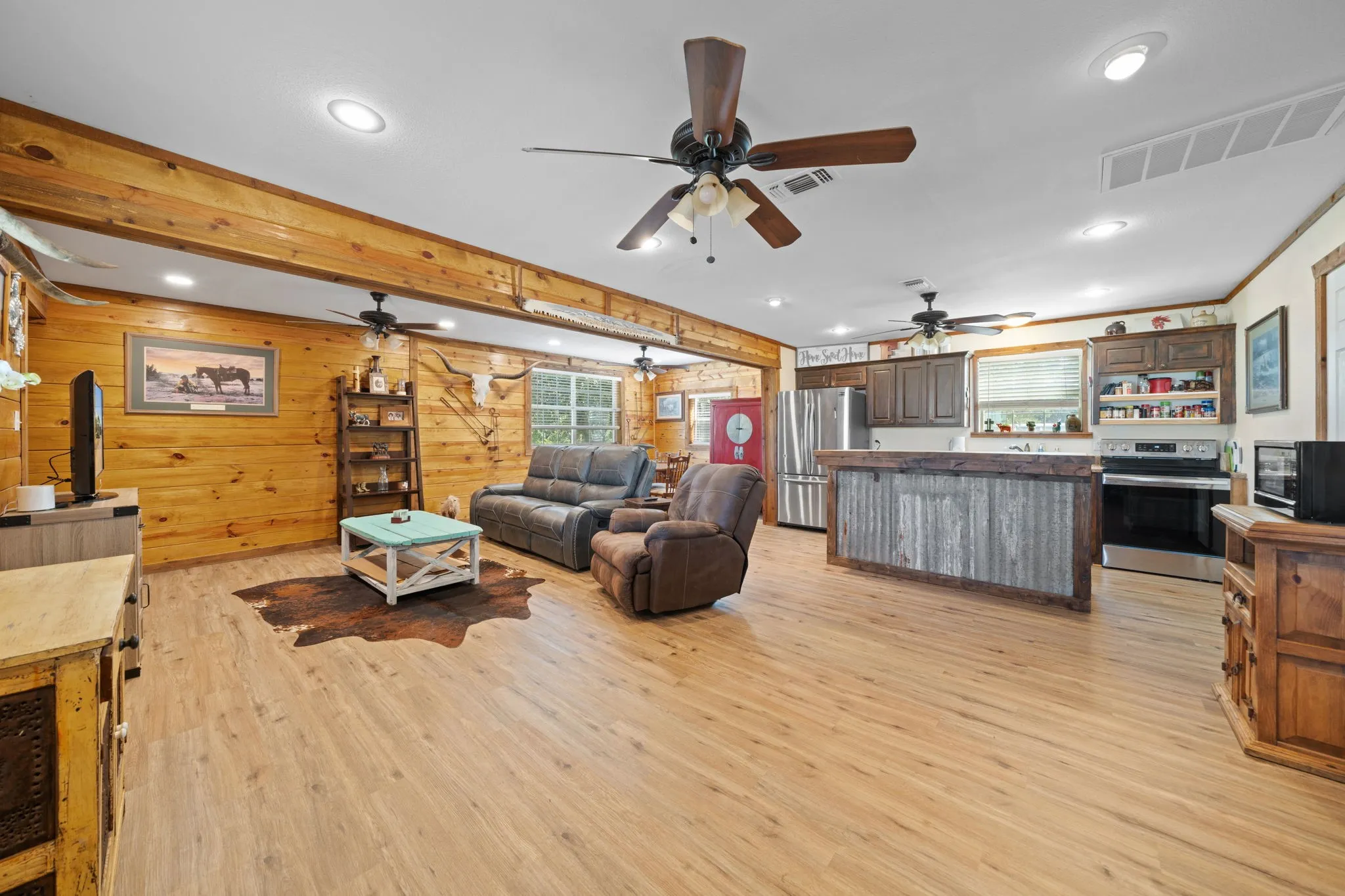 Living area with light wood-style flooring, recessed lighting, beam ceiling, and wood walls