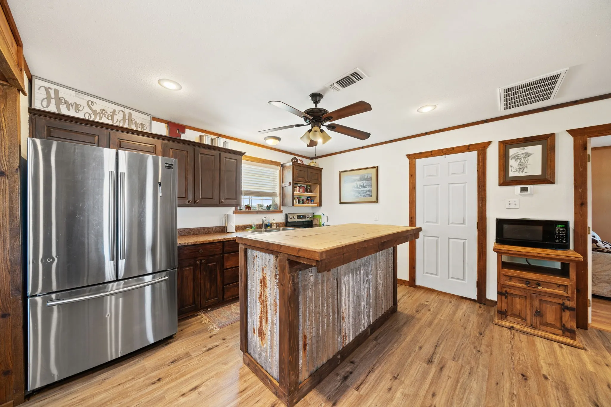Kitchen with freestanding refrigerator, dark brown cabinetry, light wood-style flooring, open shelves, and ornamental molding