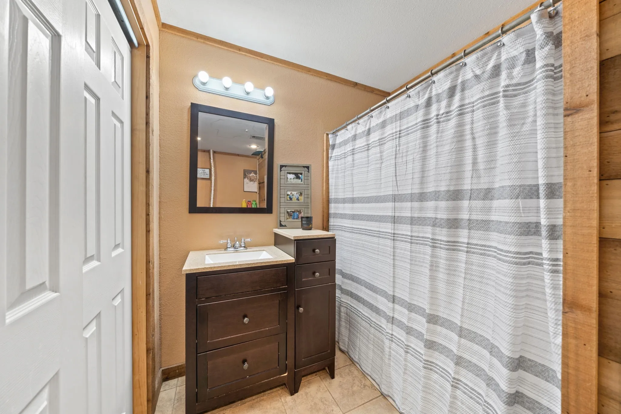 Bathroom featuring vanity, light tile patterned floors, and a shower with curtain