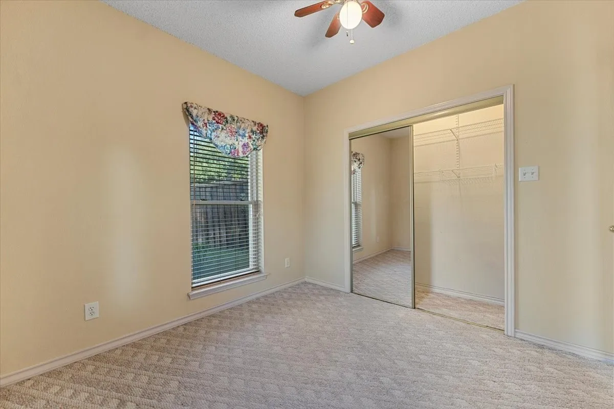 Unfurnished bedroom with carpet, a textured ceiling, ceiling fan, and a closet