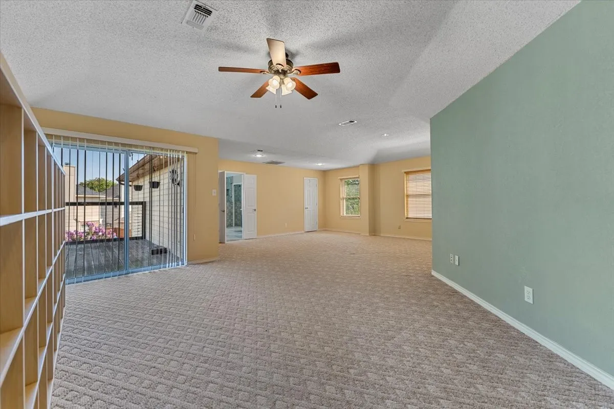 Carpeted spare room featuring a textured ceiling and ceiling fan