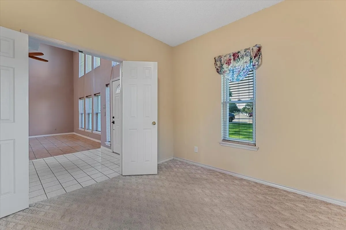 Spare room with light tile patterned floors, light carpet, and ceiling fan