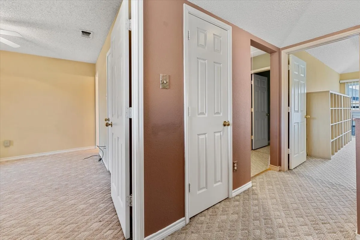 Corridor with a textured ceiling and light carpet