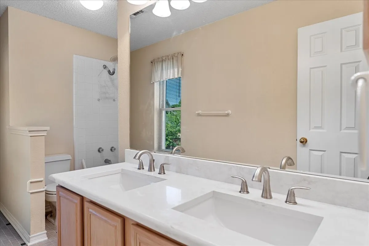 Full bathroom featuring a textured ceiling and double vanity