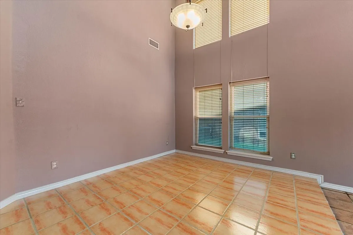 Unfurnished room with light tile patterned floors and a towering ceiling
