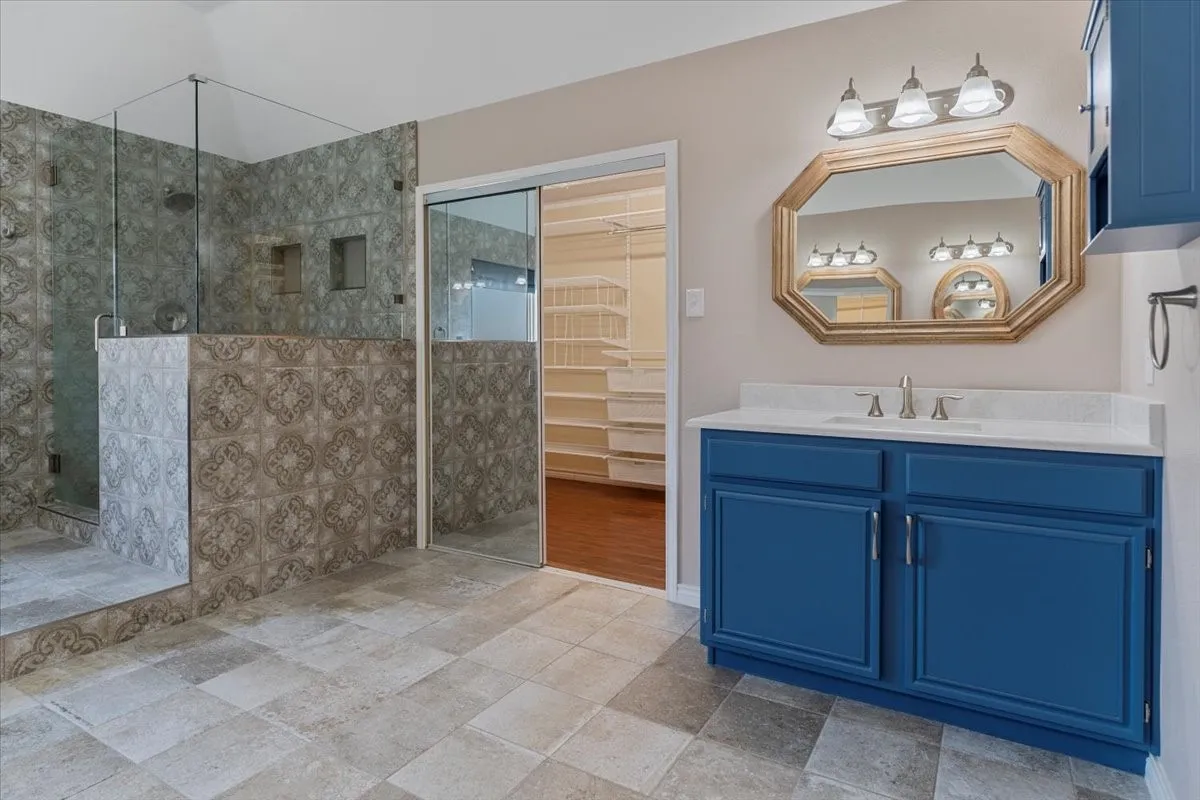 Full bathroom featuring a stall shower, vanity, and a walk in closet