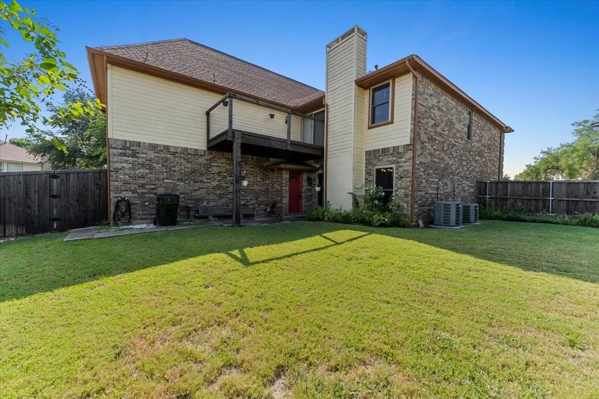 Rear view of house featuring brick siding, a fenced backyard, and a patio area