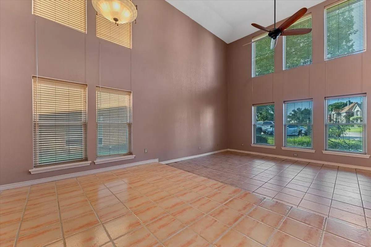 Spare room featuring light tile patterned floors, high vaulted ceiling, and ceiling fan