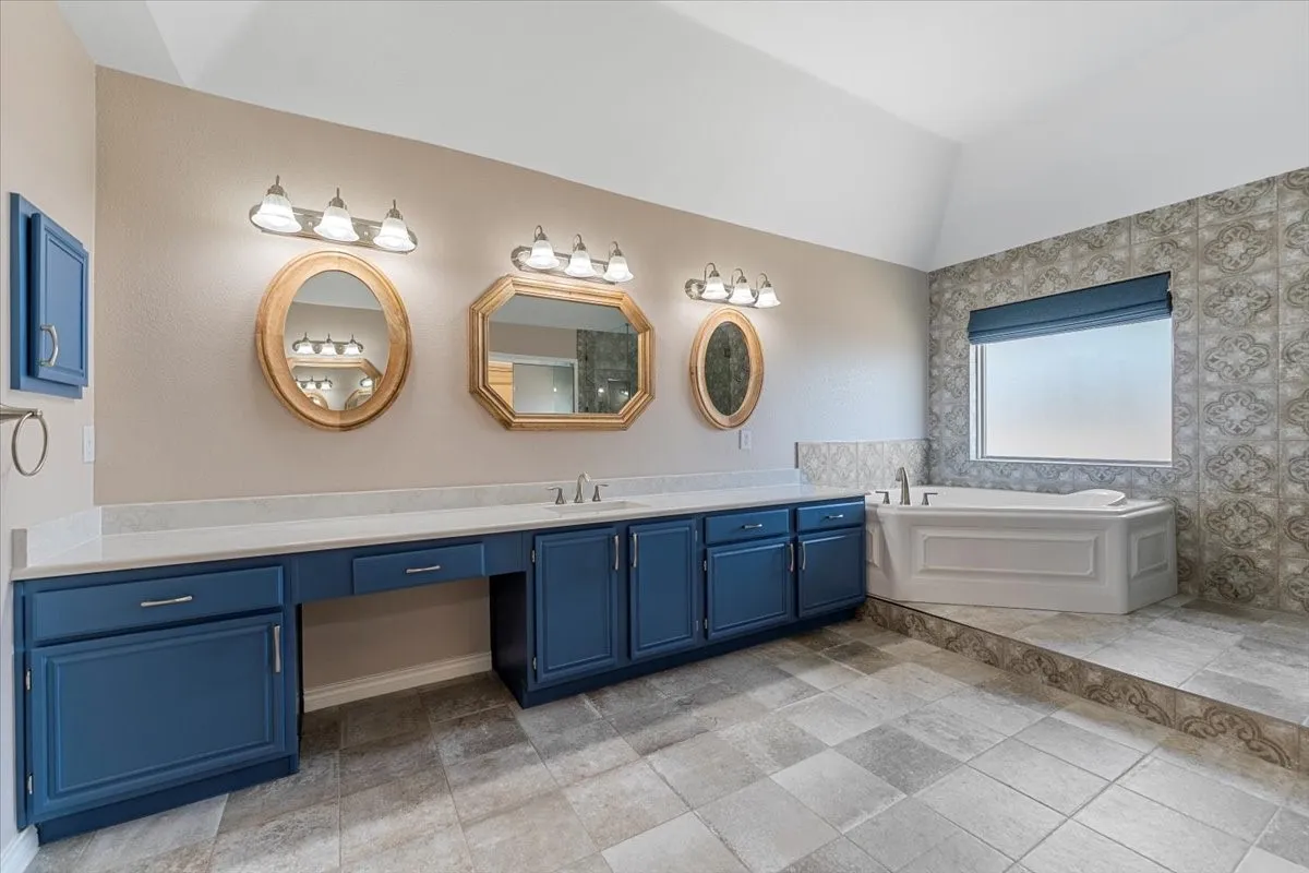Bathroom featuring a bath, vanity, and lofted ceiling