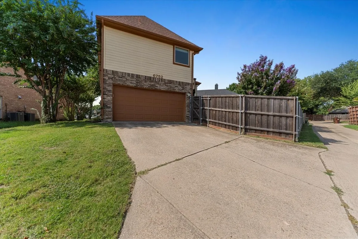 View of side of property with brick siding, concrete driveway, and a garage