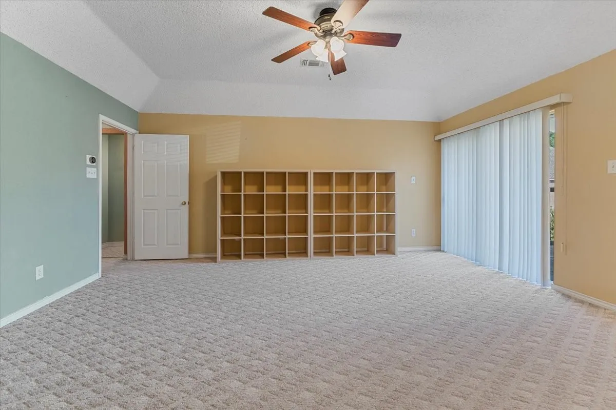 Carpeted spare room with a textured ceiling, lofted ceiling, and ceiling fan