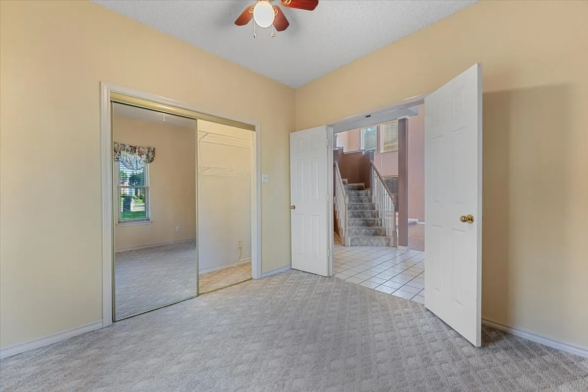 Unfurnished bedroom with carpet floors, multiple windows, a textured ceiling, and a closet