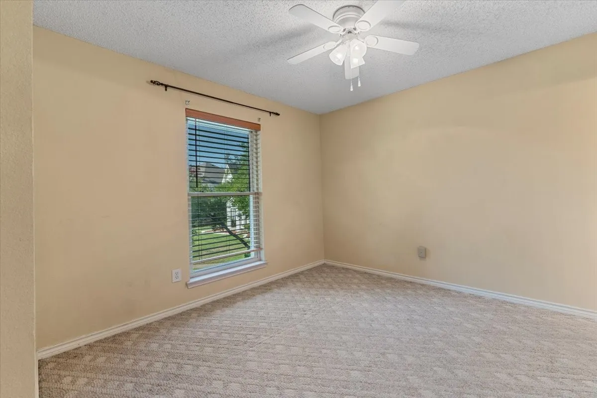 Spare room featuring a textured ceiling, light carpet, and ceiling fan