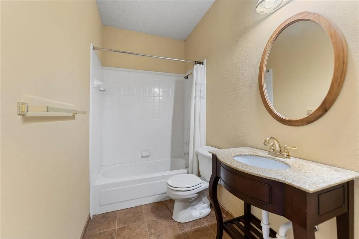 Bathroom with shower / bathtub combination with curtain, a textured ceiling, and tile patterned flooring