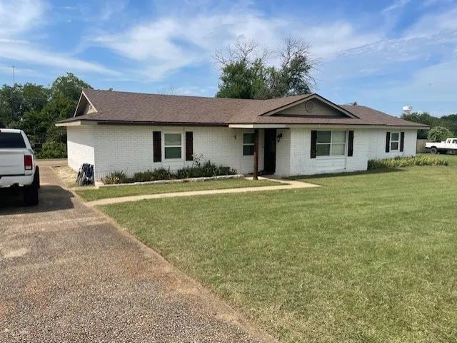 Ranch-style house featuring brick siding and a front lawn
