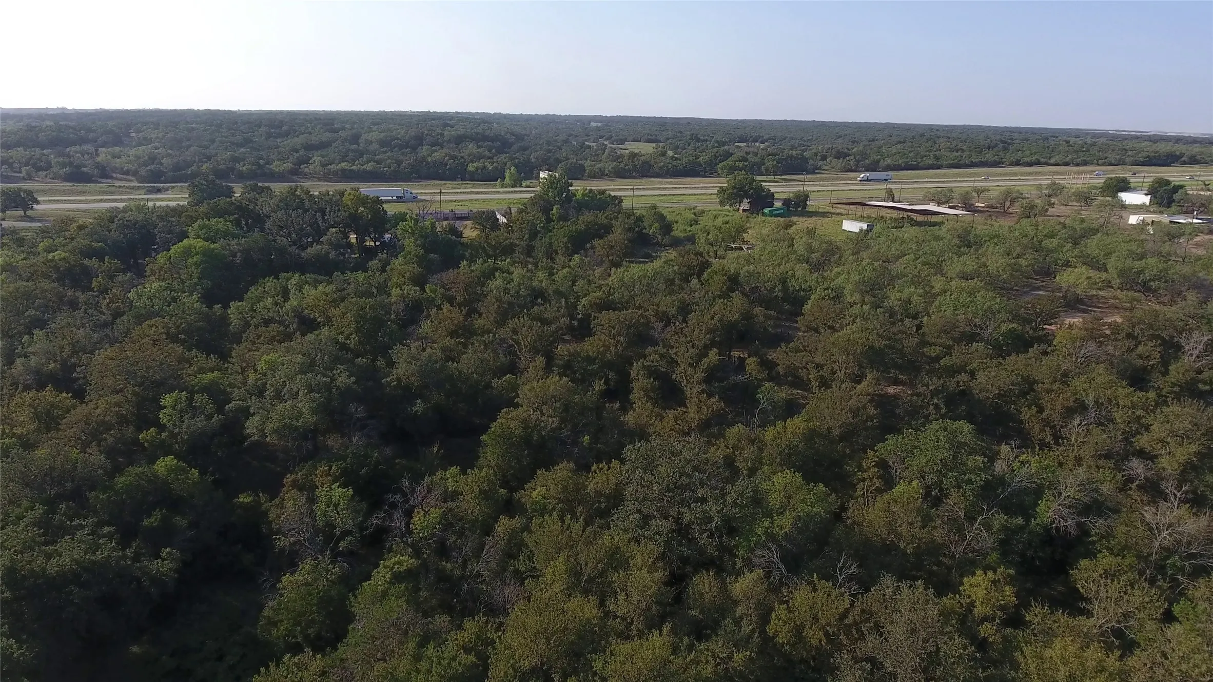 Aerial view of property and surrounding area with a forest