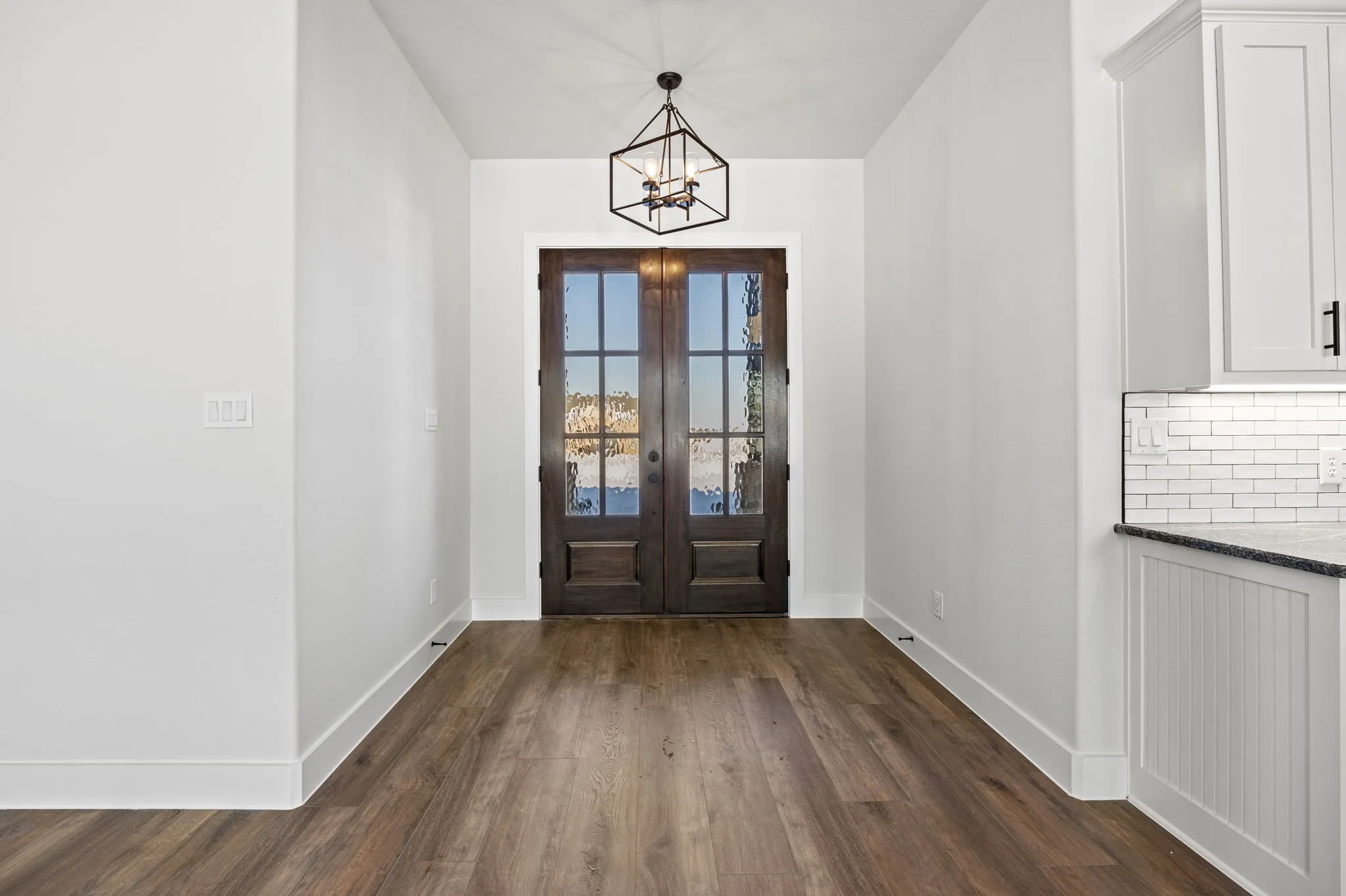 Entrance foyer with dark wood-style flooring, french doors, and a chandelier