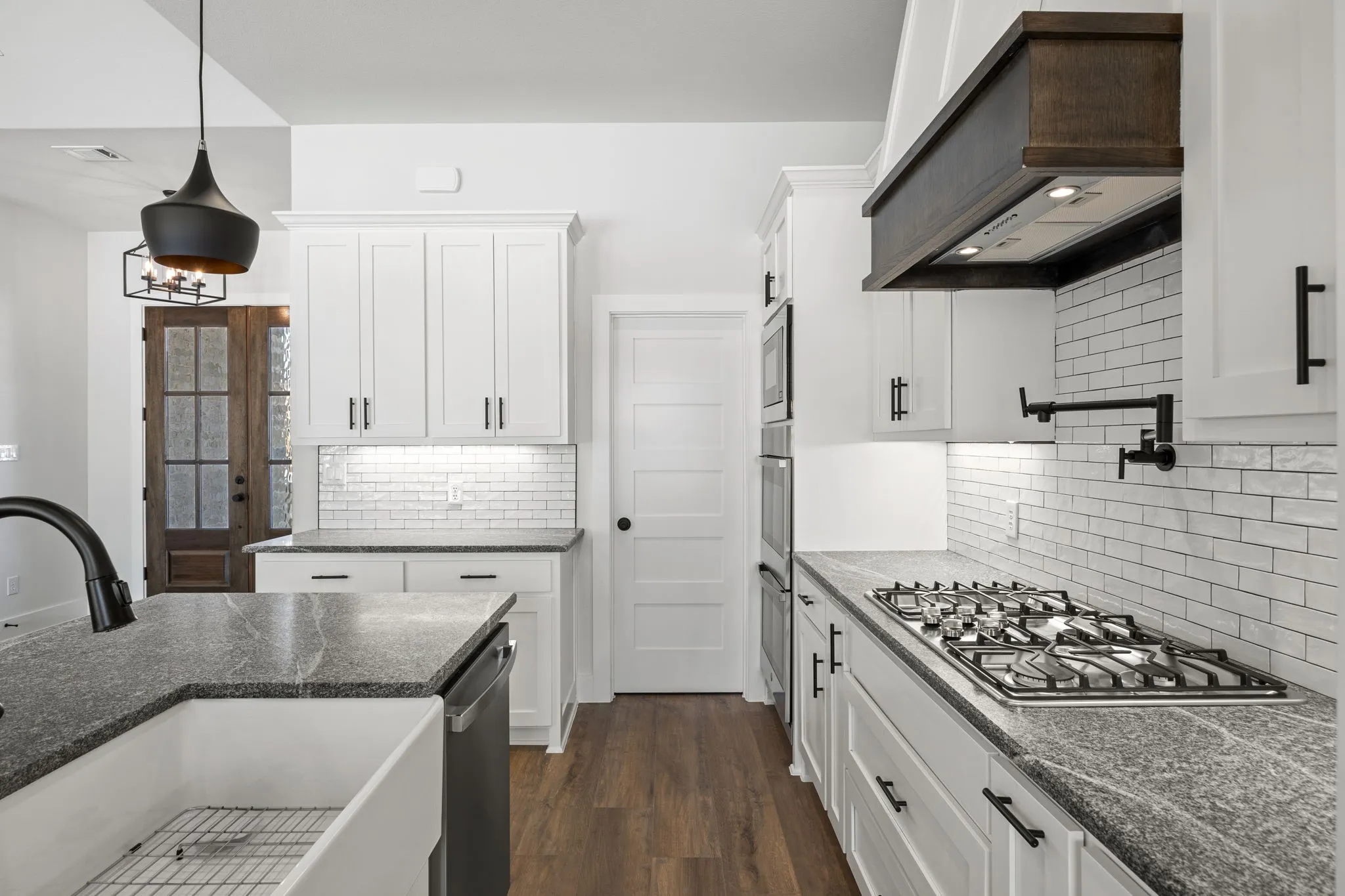 Kitchen with white cabinetry, decorative light fixtures, and dark wood-type flooring
