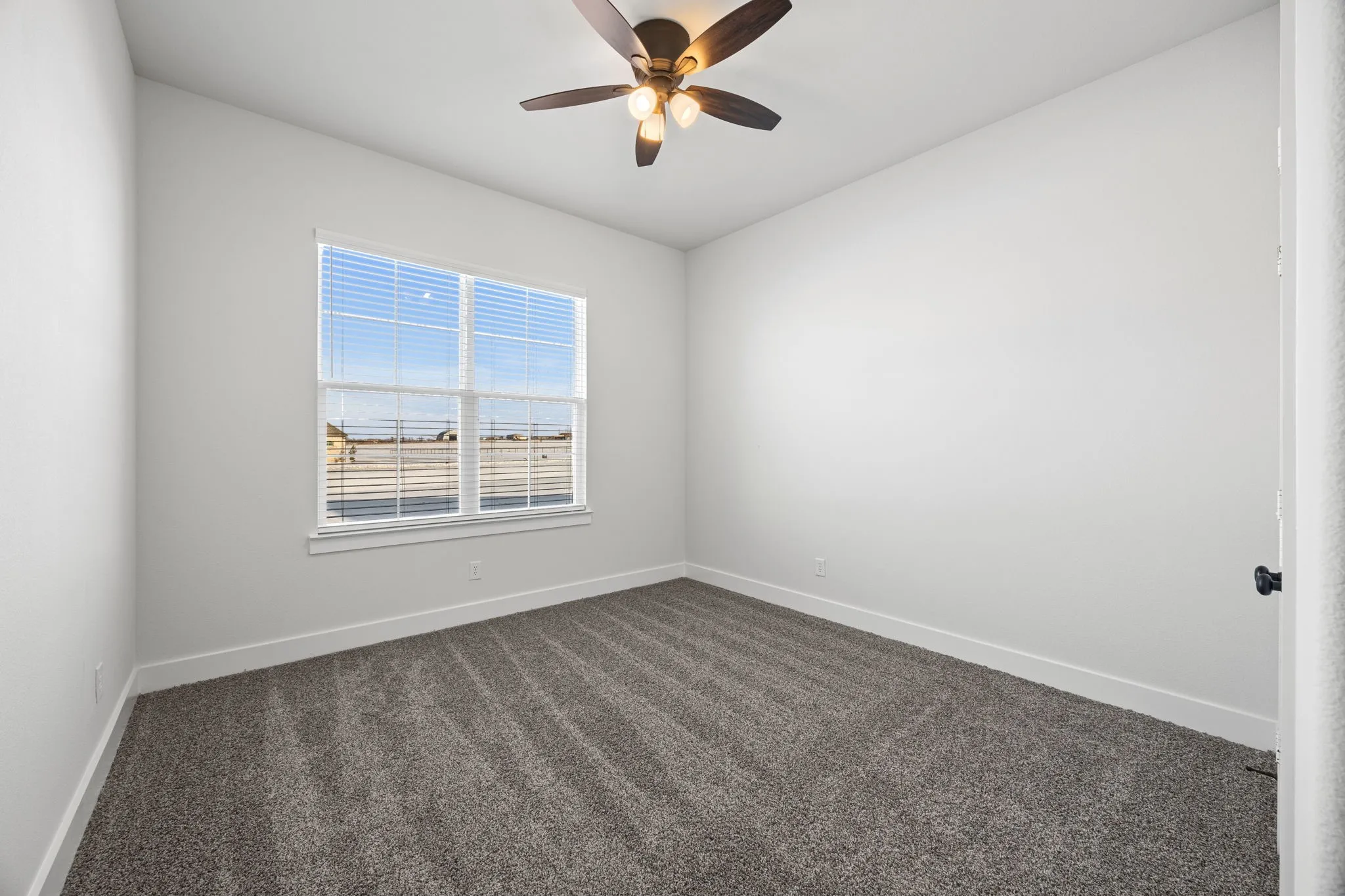 Spare room featuring dark colored carpet and ceiling fan