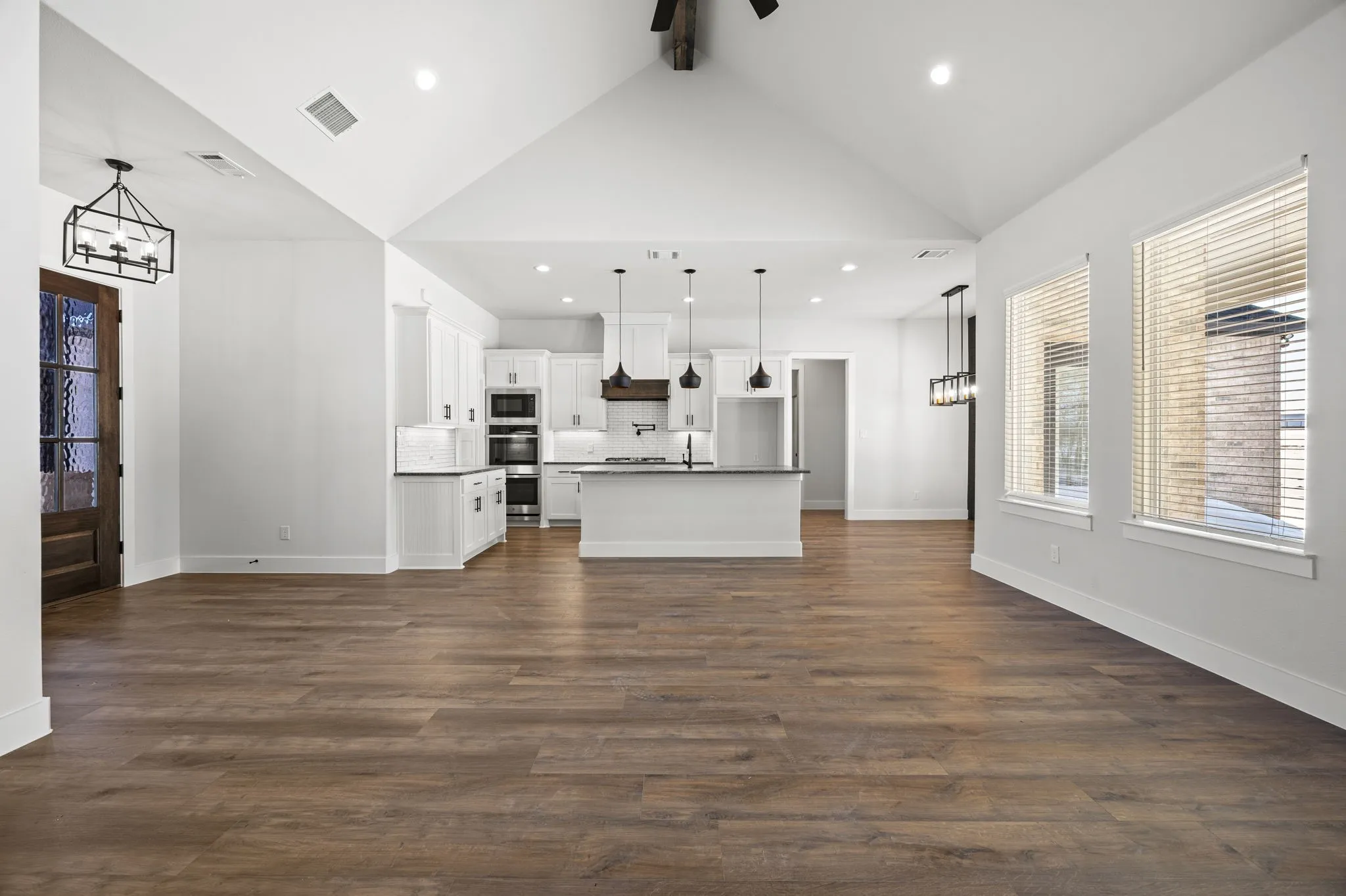 Unfurnished living room featuring a chandelier, healthy amount of natural light, and dark wood-style floors