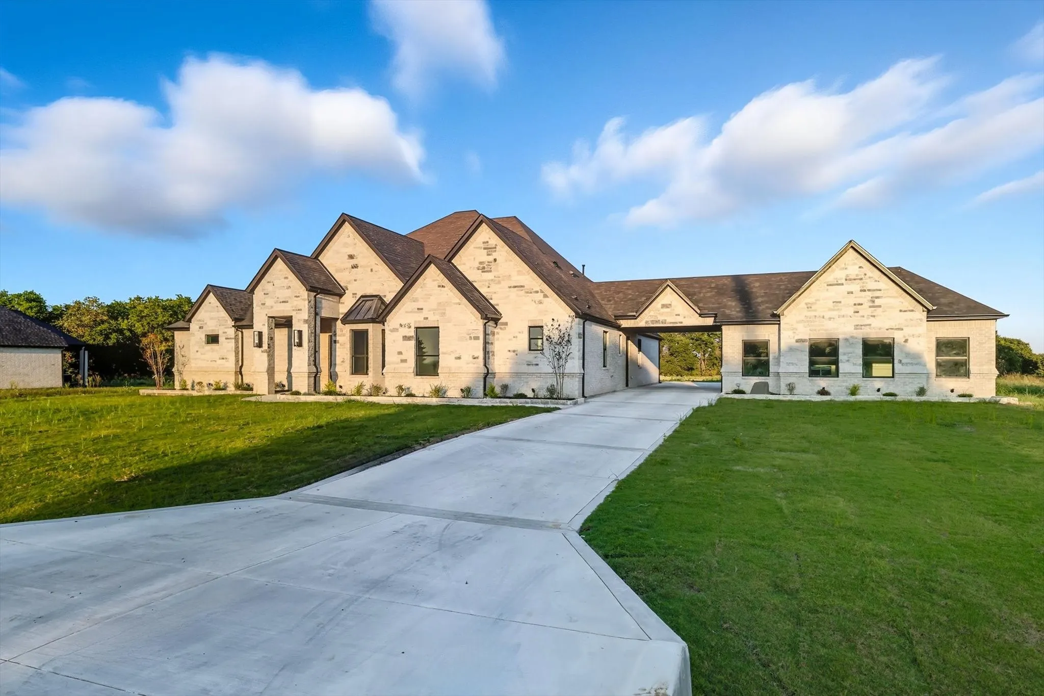 View of front facade featuring driveway, brick siding, a front lawn, and a carport